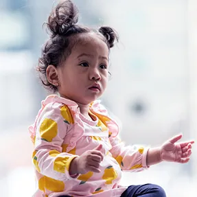 Child sits and holds out her arms