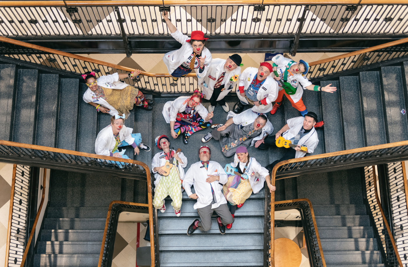 Men and women dressed as clowns pose for photo in stairwell