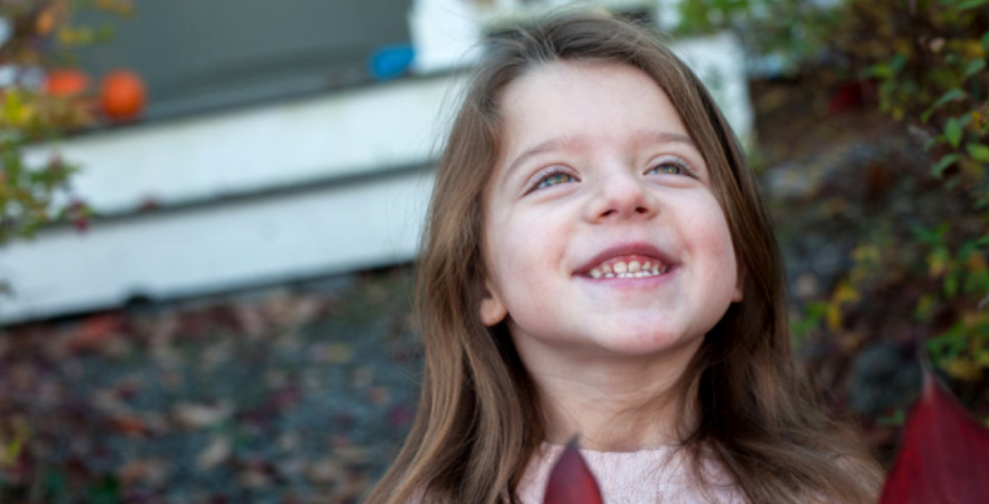 Young girl smiling while tilting her head upward