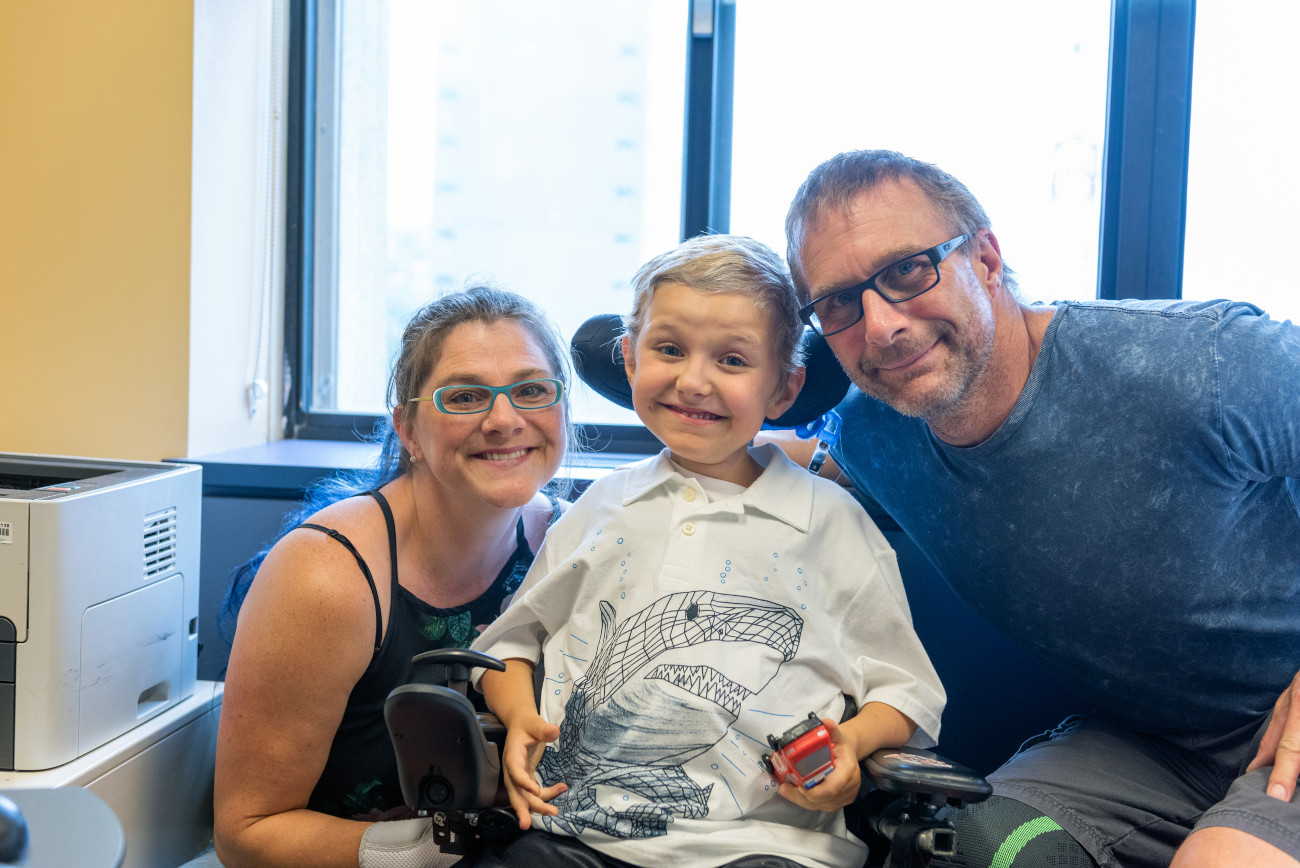 Mom (left), dad (right) pose with son in wheelchair (center)