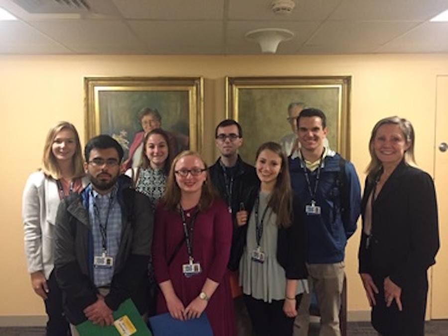 eight men and women standing in front of two paintings 