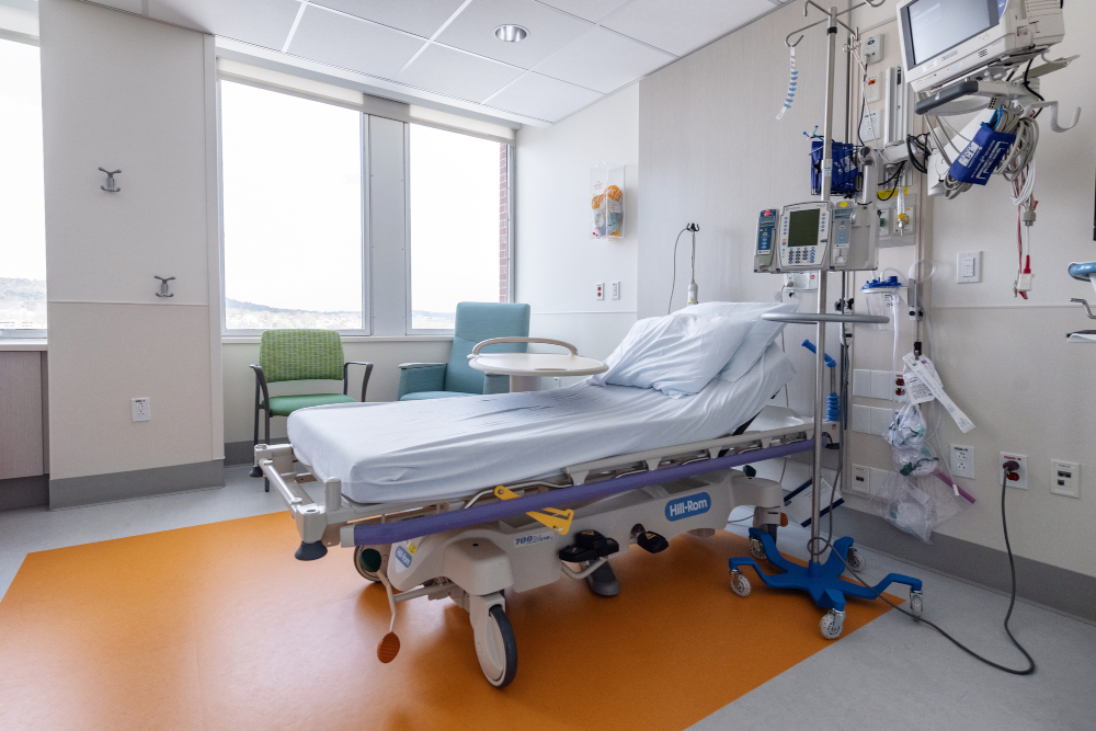 Hospital room with bed, medical monitoring equipment, and chairs