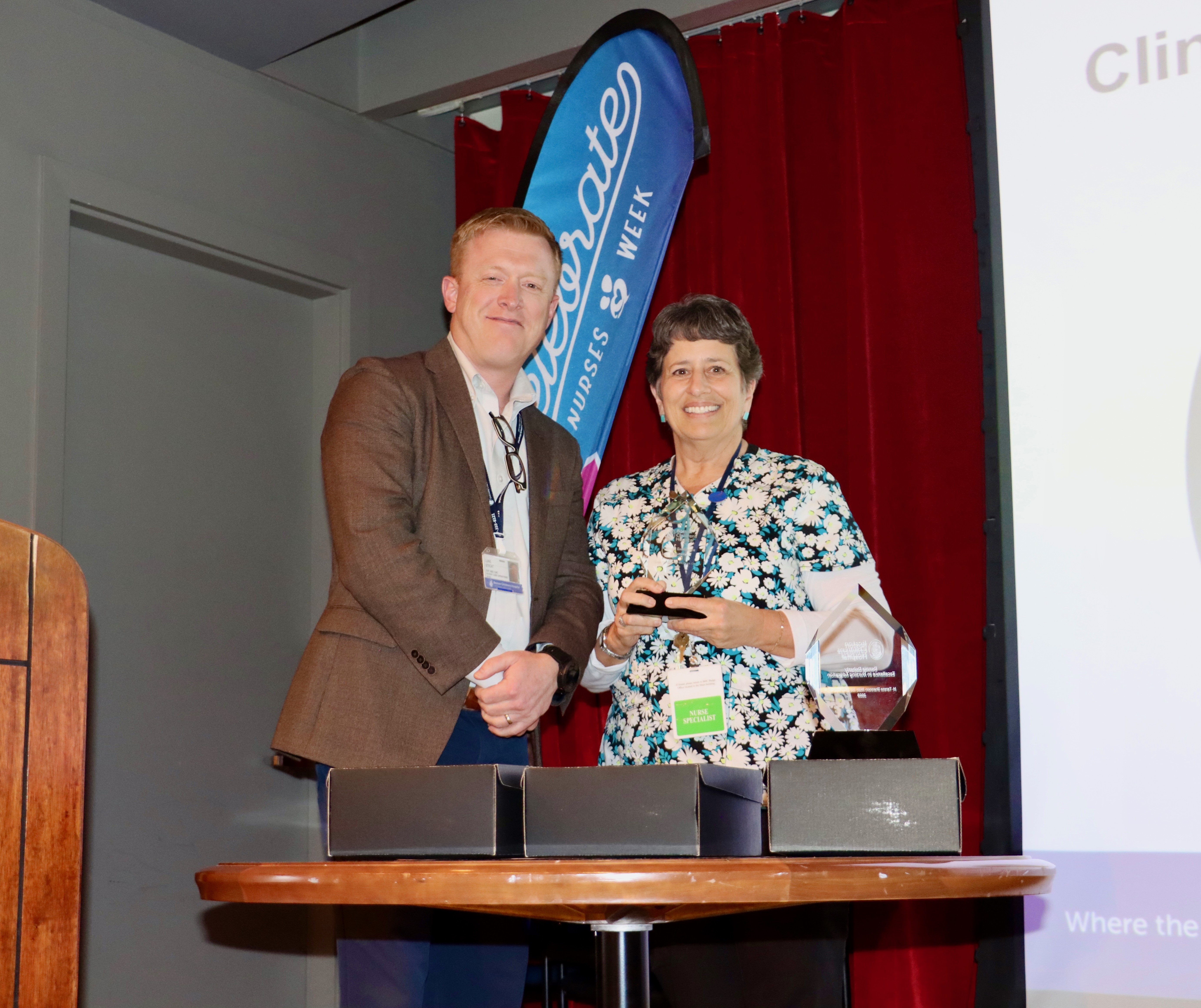 A woman, Sue Hamilton, holds a trophy in her hands while a man poses next to her. 