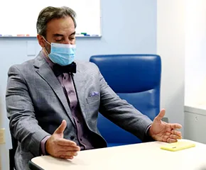 Man wearing clinical facemask sits at desk