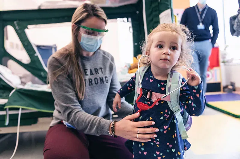 a girl wearing a backpack with her mother