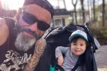a father wearing sunglasses and a bandana and a young daughter smiling at the camera