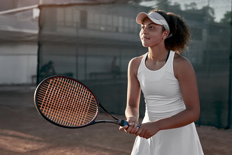 Woman holds tennis racquet while awaiting a volley.