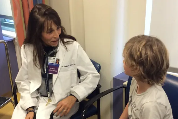 Clinician sitting in chair speaks to boy who's sitting down