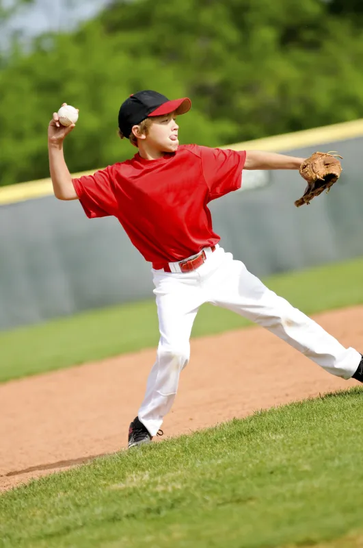 Young baseball player throws with right hand from far side of the diamond.