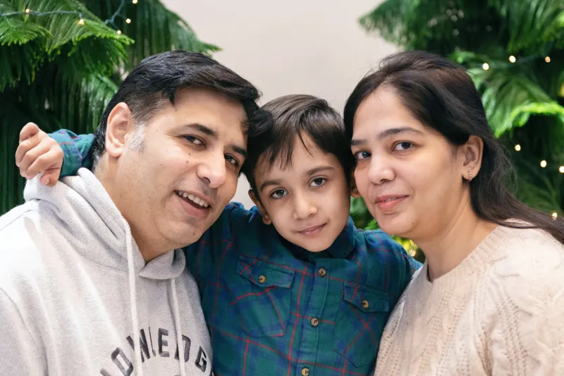Young boy embraces parents who are standing next to him