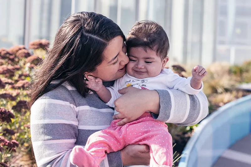 Mom holds young daughter in Boston Children's garden