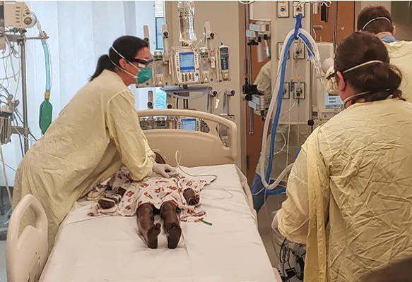 Three doctors surround a simulation model to practice a procedure. 
