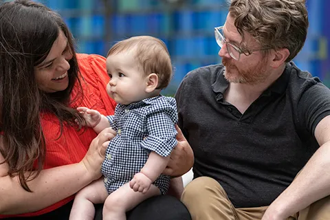 Woman and man gaze at baby held in woman's arms