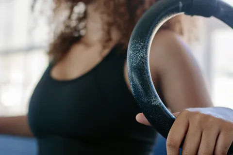 Female athlete holds onto gymnastic ring with left hand