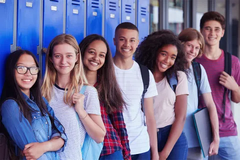Seven teenagers pose in front school lockers