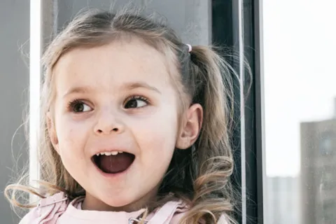 Young girl with hair in pigtails has a wide smile