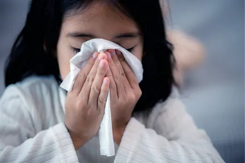 Girl blows nose into tissue