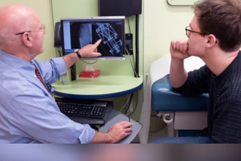 Clinician, at left, points at medical imagery while chatting with young man at right